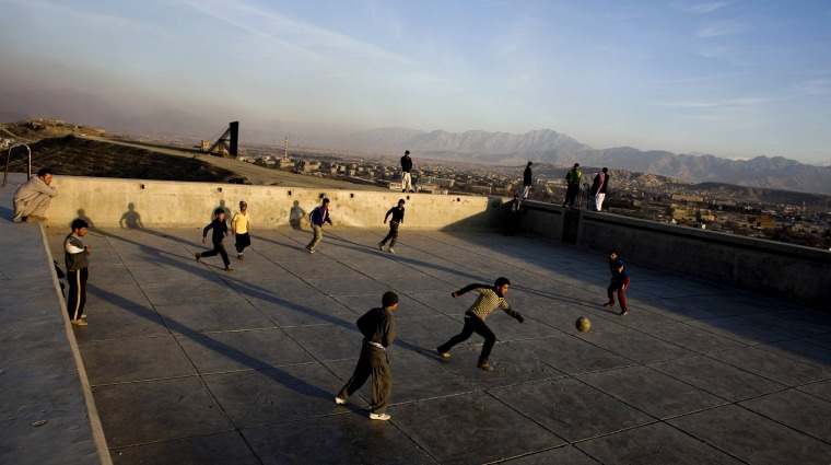 Image: Afghan men play soccer in an old swimming pool on the hill in Kabul